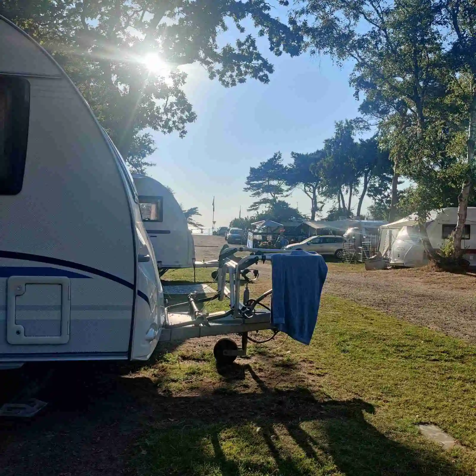 En campingplats vid Lerbergets camping med flera husvagnar och en husbil parkerade på gräsbevuxna platser, omgivna av grönska.