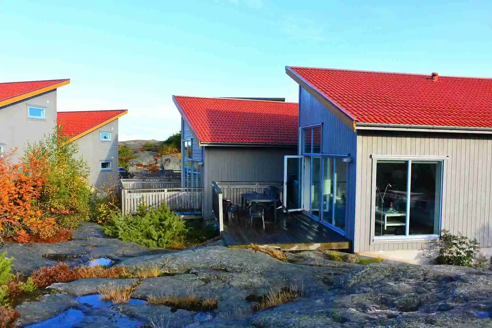 En mysig stuga med sittgrupp utomhus, omgiven av grönska, vid ett ekohotell i Skärhamn.