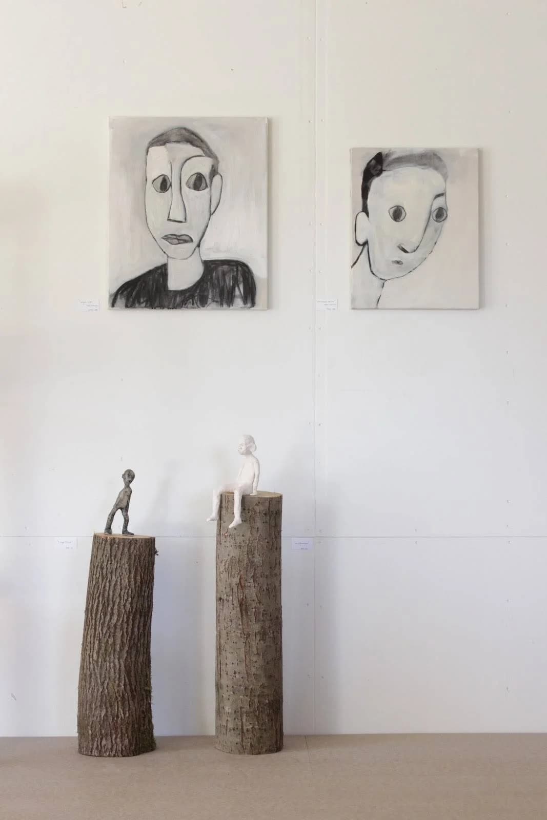 En konstutställning i en pionjärgård visar modern konst och kreativa konstverk, inramade i olika bildramar, och gjorda av naturliga material.