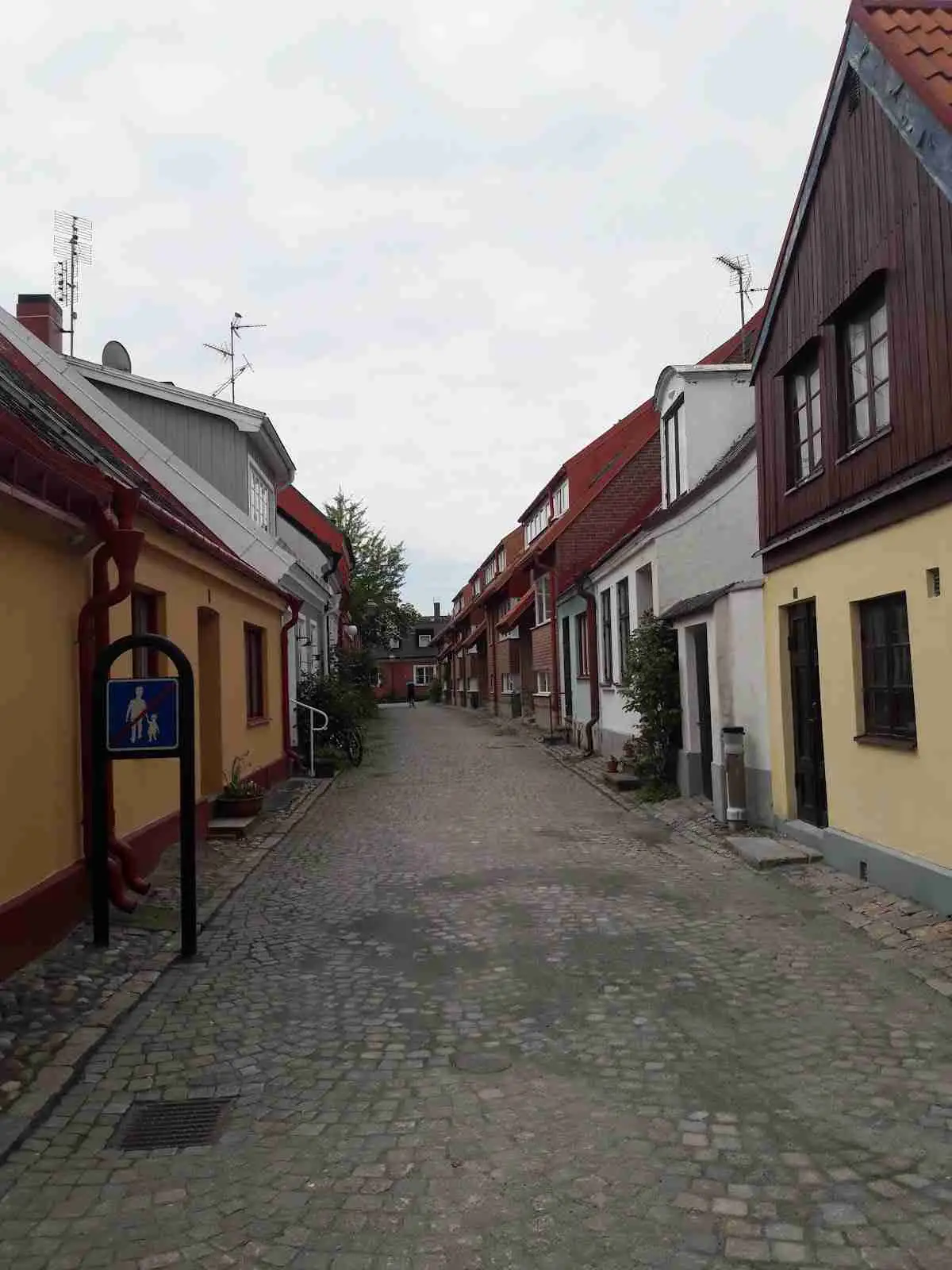 Alt-text: En gata i ett bostadsområde med kullerstenar och omgivande hus vid Fredriksbergs kursgård-camping.