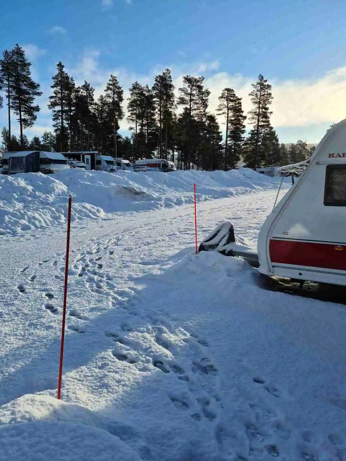 En snötäckt campingplats i Vemdalen med husvagnar och husbilar omgivna av snö och is under en vinterdag.