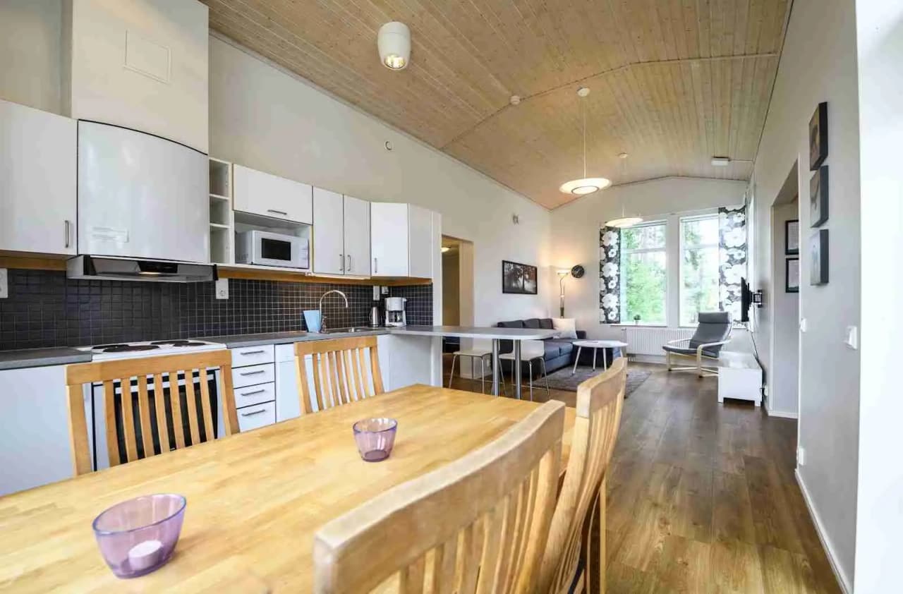 En stuga med trädetaljer inredd som en semesterbostad, med möbler i trä, trägolv och ett ljust innertak.