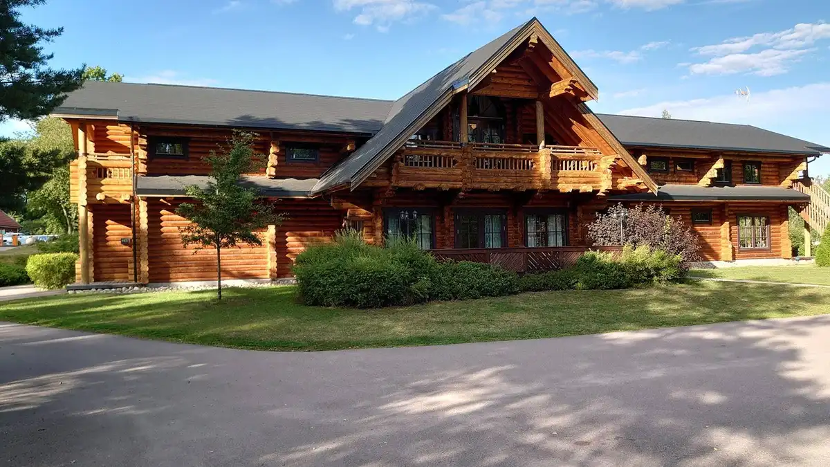 En röd stuga med vita knutar omgiven av en grön gräsmatta vid Herrfallet AB.