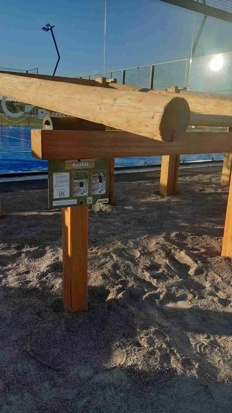 En närbild av träplankor med olika nyanser av träbets, i bakgrunden skymtar skogsmiljö.