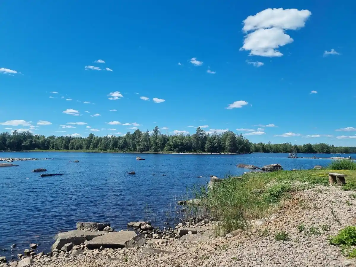 En somrig dag vid Alsterbro camping med blå himmel och moln över en lugn vattenväg.