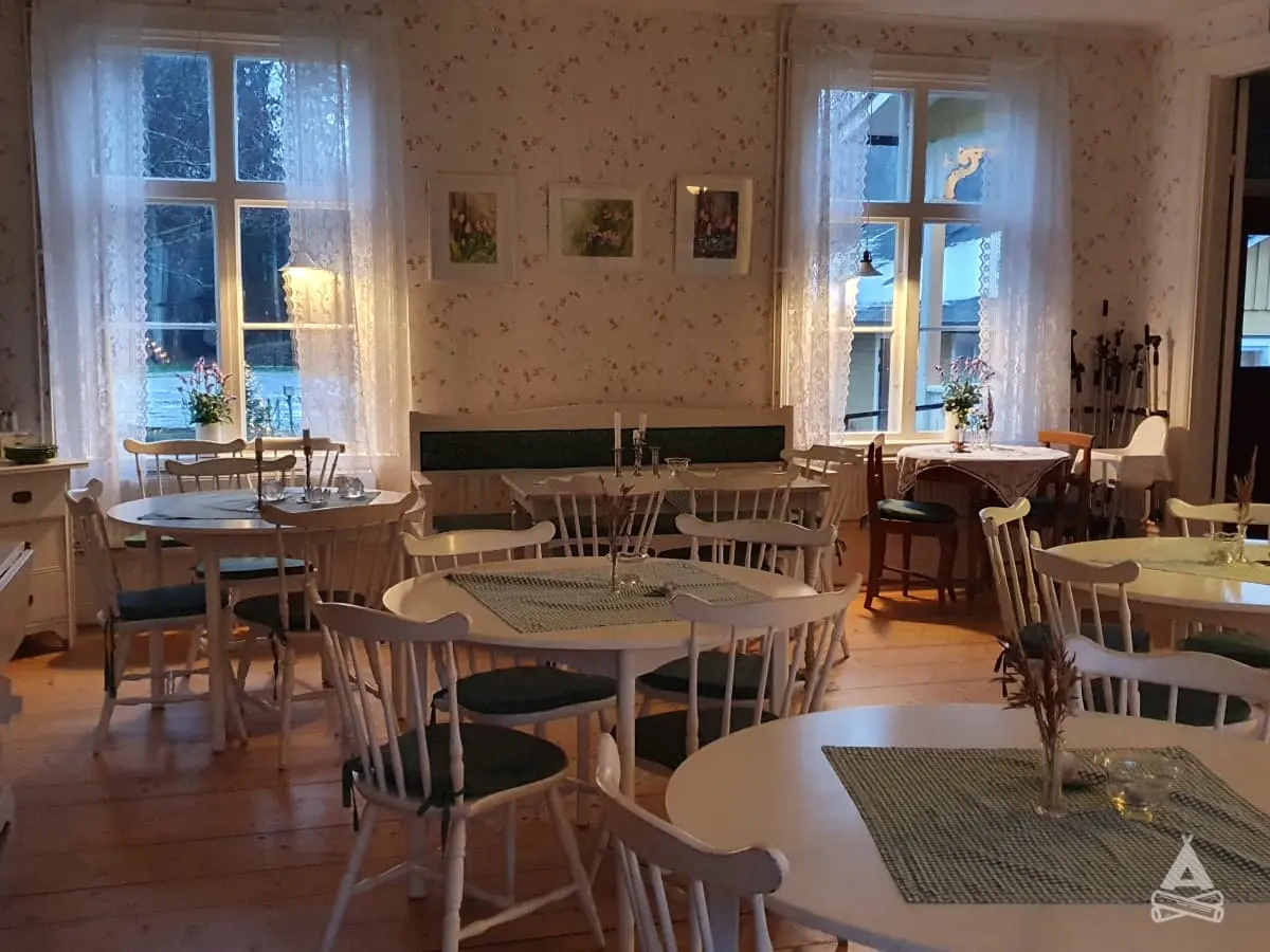 Ett ljust och inbjudande matrum på Sofielund vandrarhem & camping med flera bord och stolar. Rummet har en stilren inredning med ljusa golv och dukade bord, vilket skapar en trivsam atmosfär för måltider och gemenskap.