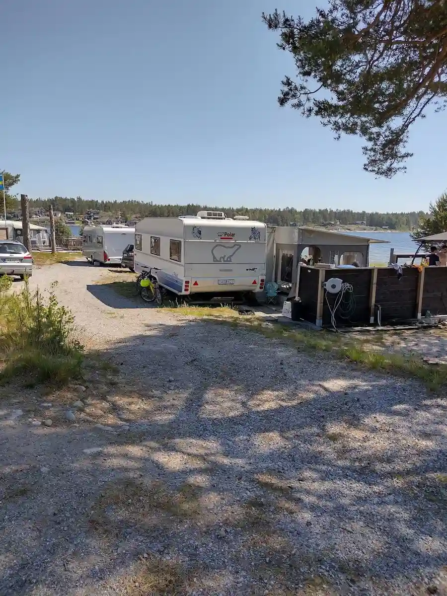 En parkeringsplats vid Ava Havsbad och Camping med flera husvagnar, husbilar och bilar uppställda på rad i bakgrunden.