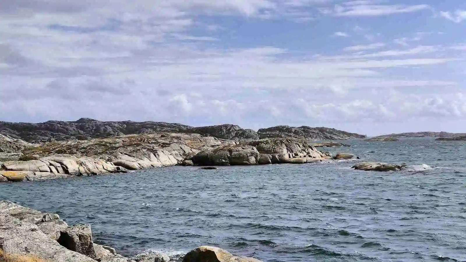 En naturskön kuststräcka vid Mossholmen med klippformationer och en vidsträckt utsikt över havet.