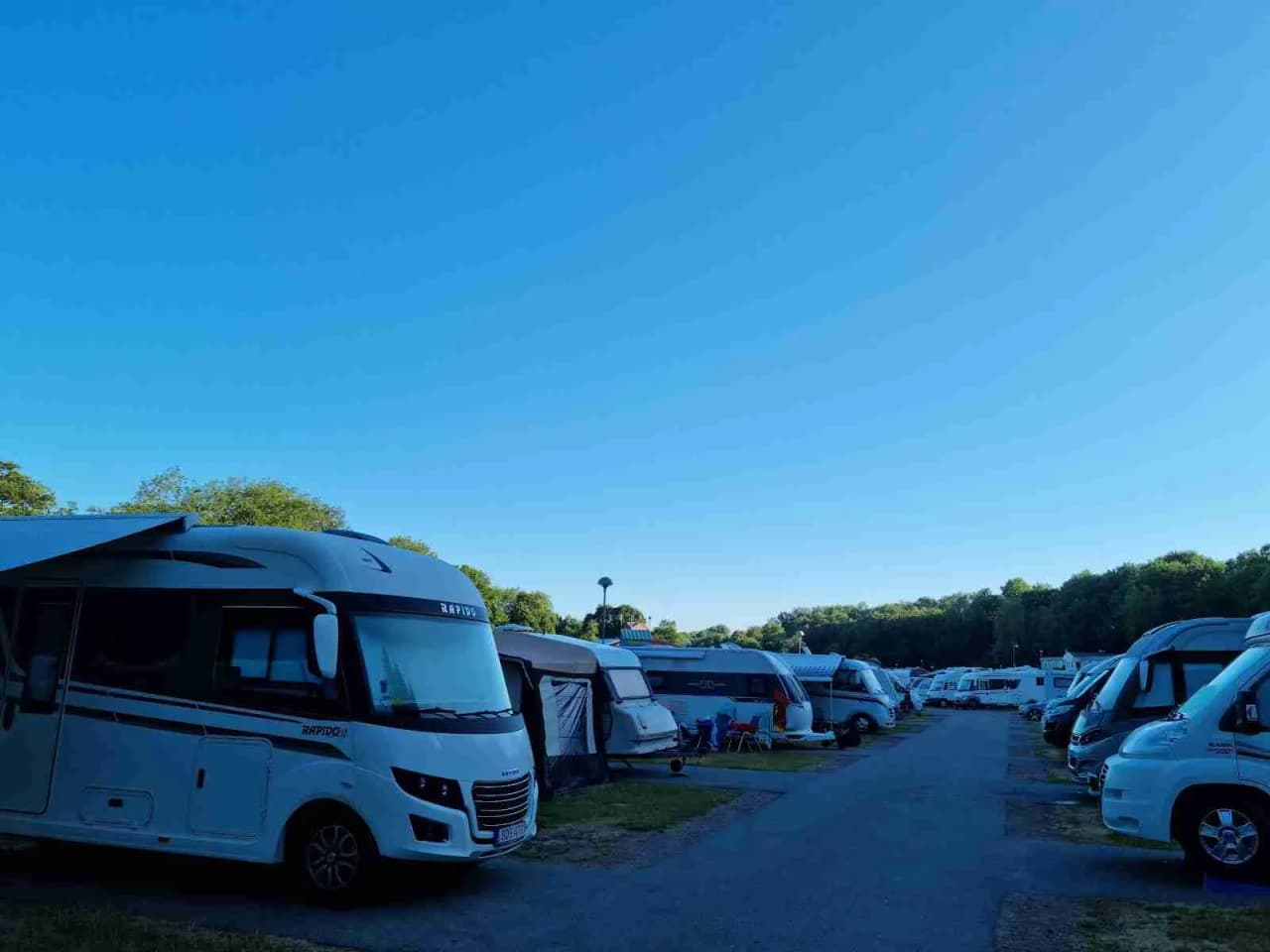 En parkeringsplats vid Lisebergsbyn med bilar, husbilar och en lyxbil parkerade.