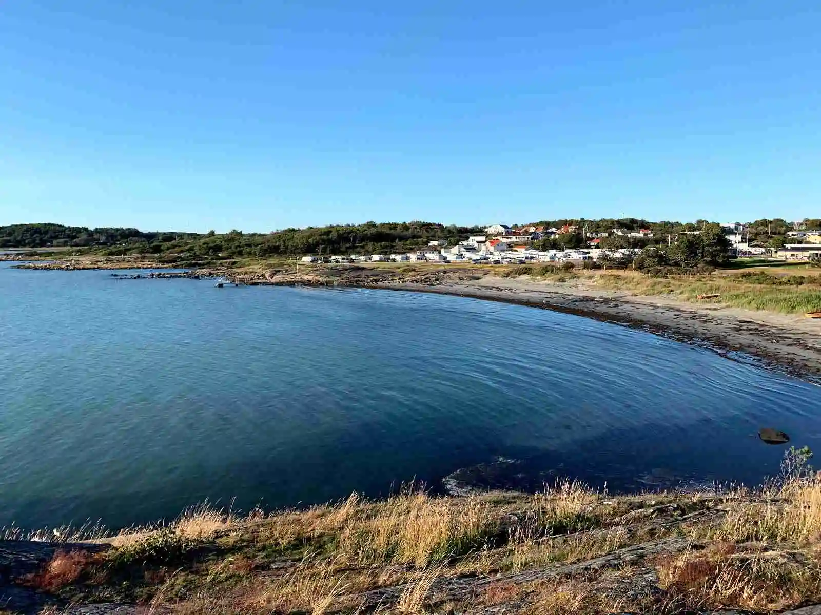 En kustlinje vid Vallersvik Camping och Hostel med havet som sträcker sig mot horisonten under en klar himmel.