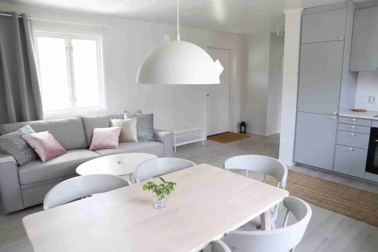 Ett modernt inrett rum på Tingsryd Resort med trägolv, en grå soffa, träbord och träpaneler i taket. Ljuset strömmar in och skapar en inbjudande atmosfär.