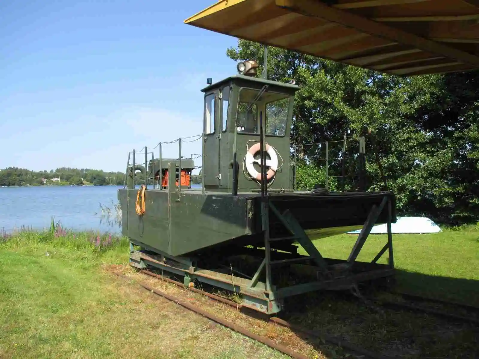 En bild av fler båtar förtöjda vid en brygga på Ivö Camping, omgivna av lugnt vatten och grönska.