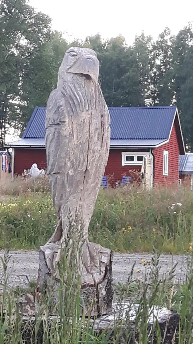 En snidad träskulptur föreställande en rovfågel, placerad som en prydnad på en grön gräsmatta vid Värmlandsgården.