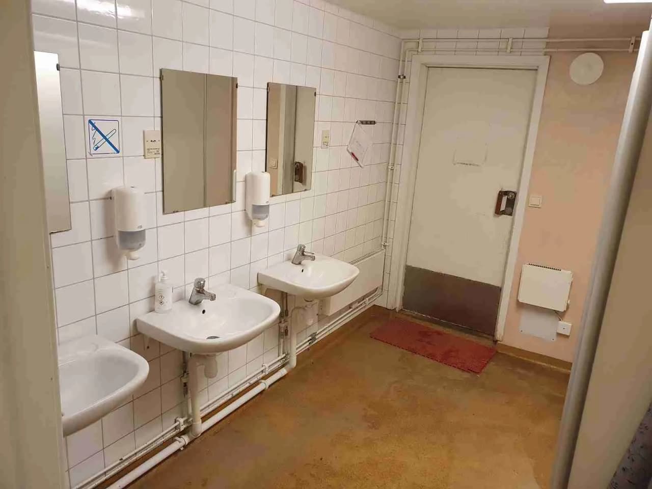 Alt-text: Ett badrumsinteriör på Bredsands Bad & Camping med ett handfat, golv i ljusa toner och moderna blandare.