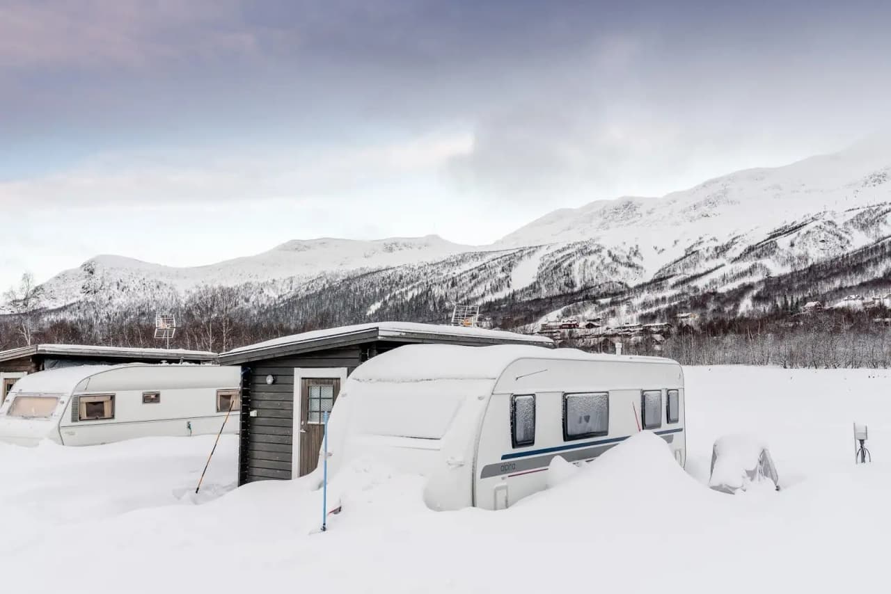 En snöklädd bergskedja i vintertid med glaciärer och is, där ett fritidsfordon står parkerat i ett naturskönt landskap.