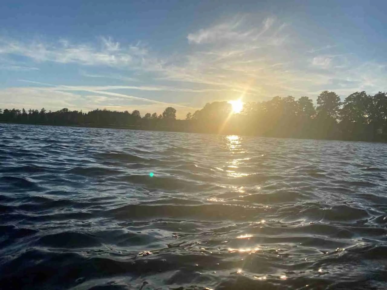 En solig dag vid Ramkvilla camping med blå himmel och horisont över vattnet.