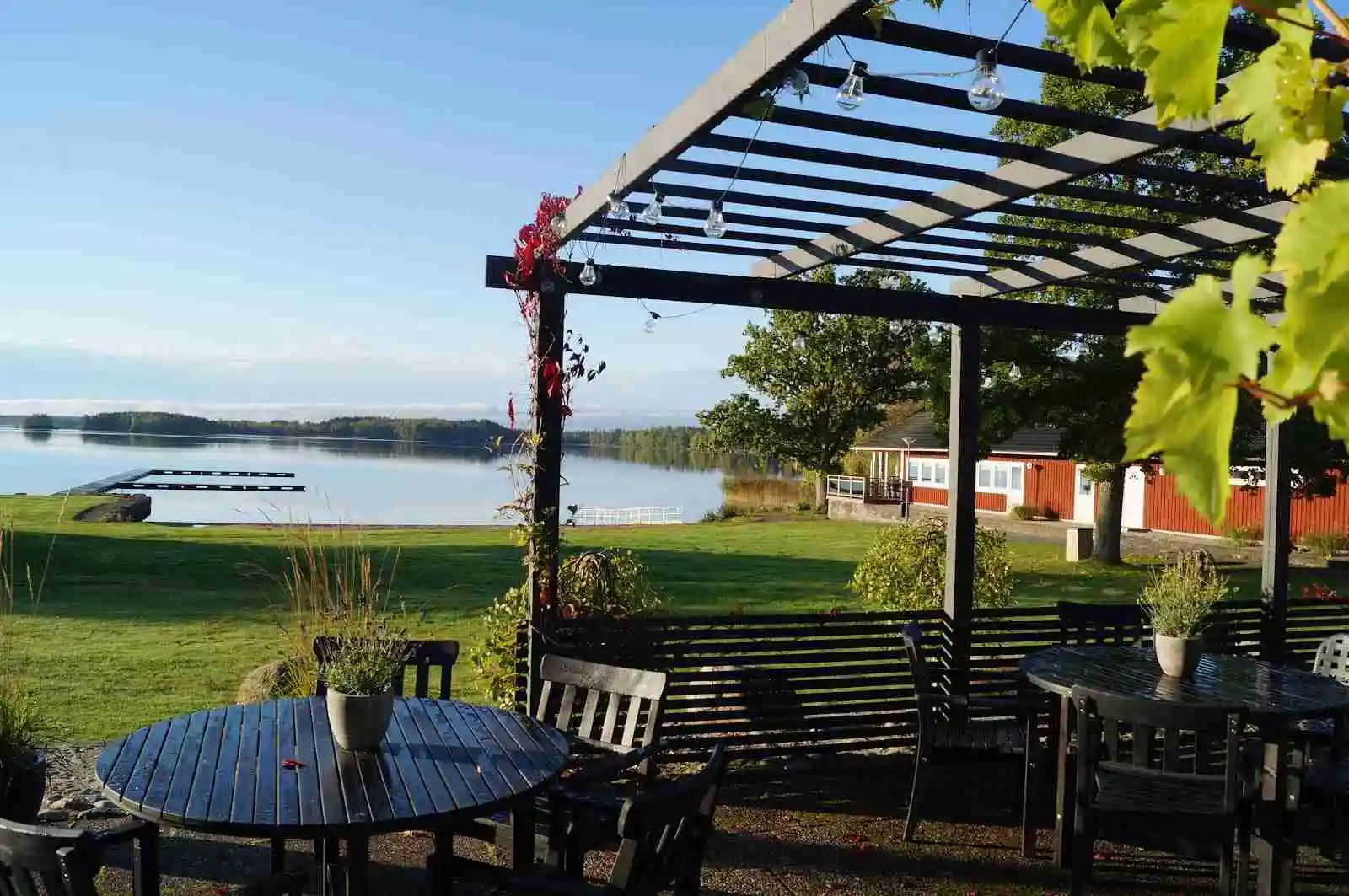 Bild av Tingsryd Resort: En vy över en fridfull sjö vid vilken det finns utomhusmöbler. Ett bord och stolar står på gräsmattan, delvis skuggade, och ger plats för avkoppling vid strandkanten.