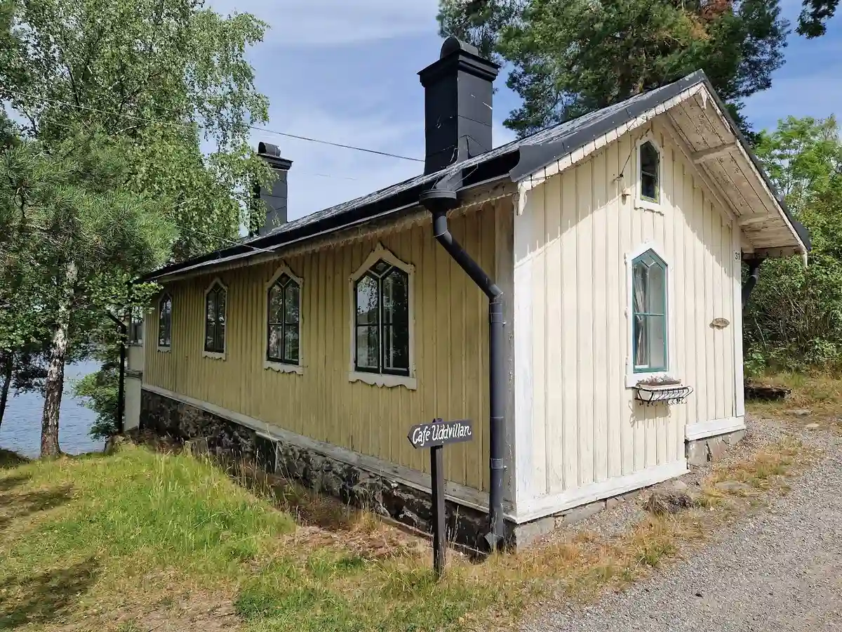 En pittoresk stuga med ett tak täckt av gröna växter, omgiven av en lantlig miljö med träd och grönska, på besöksmål Klubbensborg.