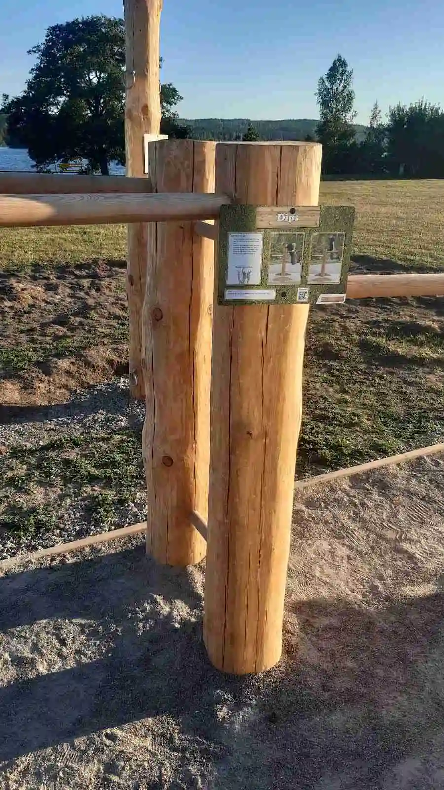 Bilden visar en naturskön plats vid Ramkvilla Camping med ett staket av träplankor som avgränsar området.