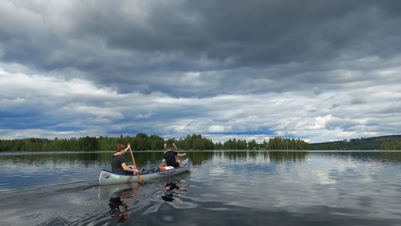 En kanot ligger vid en sjö i Värmland, omgiven av moln och lugnt vatten, perfekt för paddling och friluftsliv.
