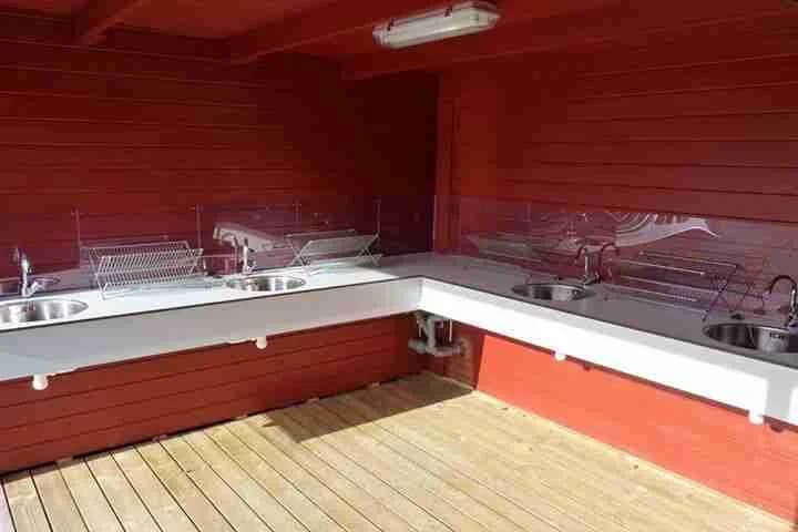 En bild som visar en trästruktur med polerade träplankor och en skyddande ytbehandling, möjligen en del av en veranda eller ett utomhusdäck vid Camping Alevi.