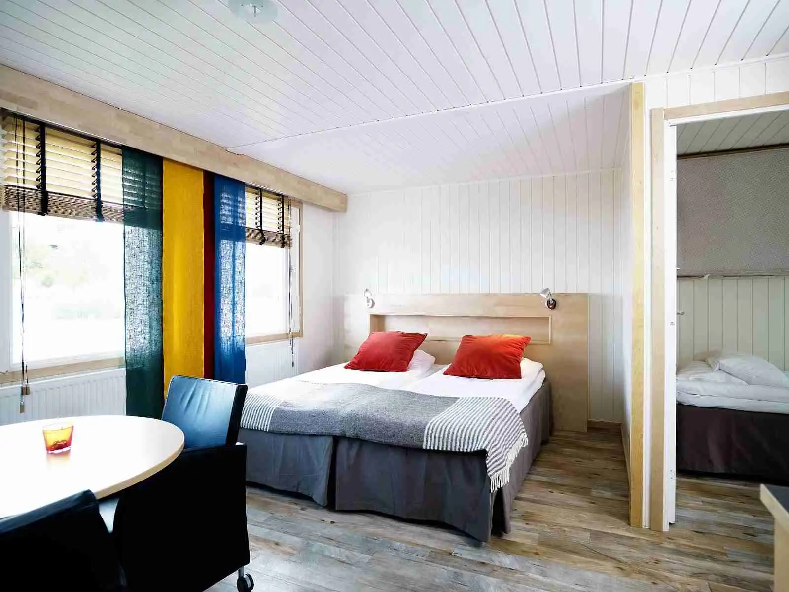 Ett stilrent sovrum med trägolv och trädetaljer i inredningen. Ett stort ljusinsläpp från takfönstret skapar en ljus och luftig atmosfär. I rummet finns en bekväm säng och modern belysning som kompletterar den eleganta inredningen.