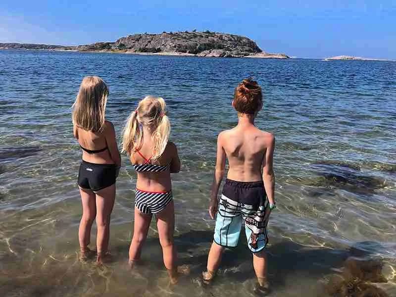 En somrig strand vid Kyrkviken med glada människor som njuter av sol och hav, en perfekt plats för avkoppling och semester.