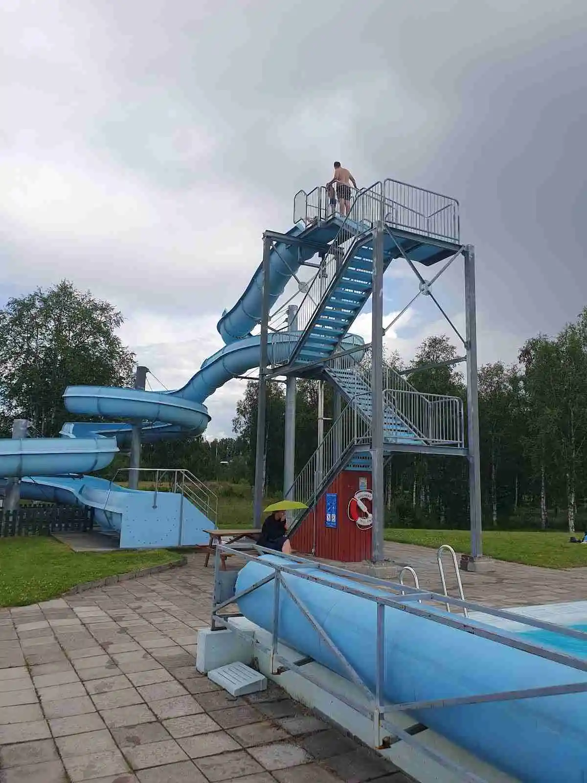 En livlig campingplats med en pool och vattenrutschbanor, omgiven av grönska och rekreationsområden, perfekt för familjesemester och utomhuslek.