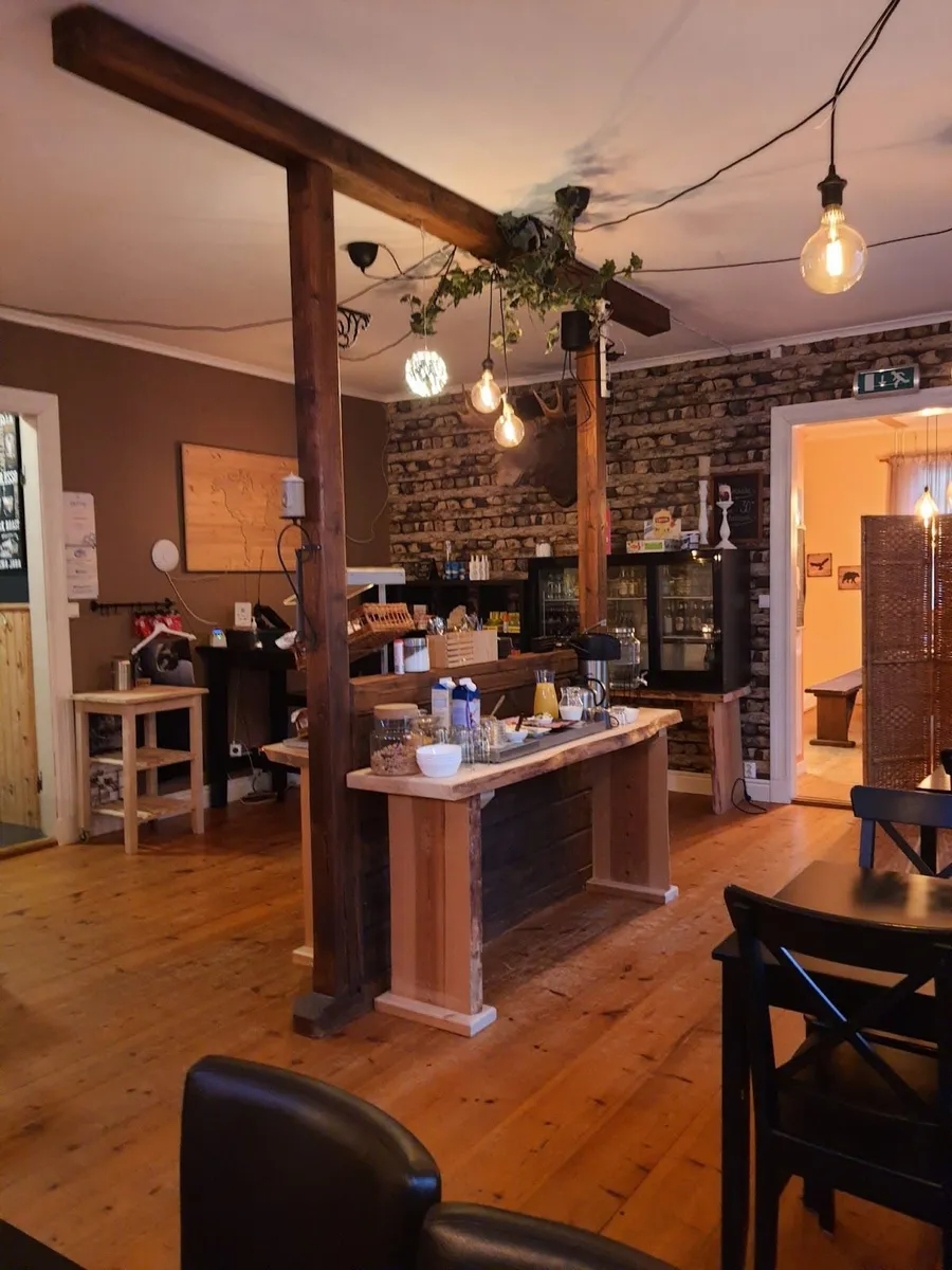 En mysig träinteriör med bord, stolar och taklampa i Wildlife Sweden Camp Ängra.