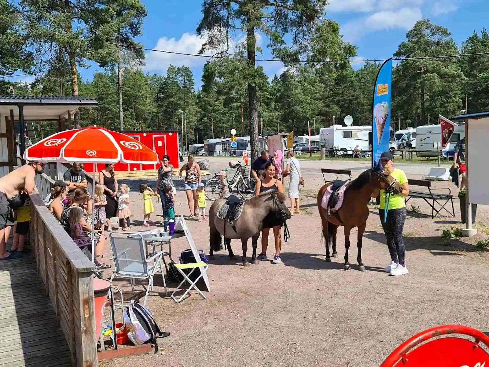 Bild på en familj som rider lugnt på hästar i ett rekreationsområde vid Gävle Camping Engesberg. Stämningen är avslappnad och naturen omkring är grön och inbjudande.