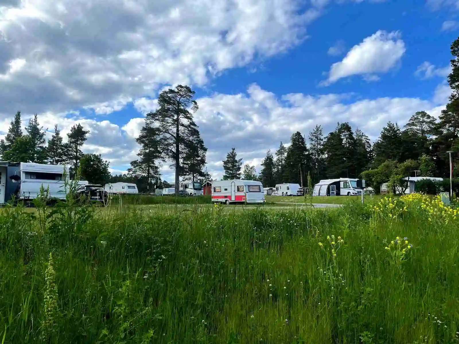 En campingplats i Gävle med gräsytor och husbilar, omgiven av ängar och öppna fält.