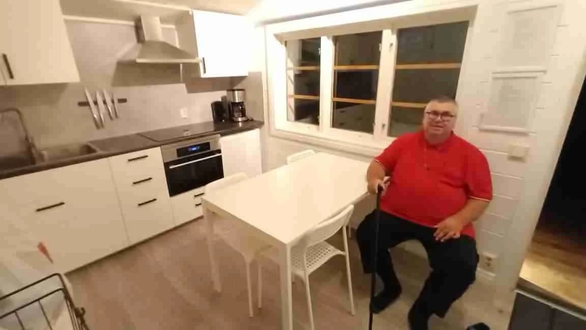 En interiörbild av ett campingkök i Malexander Camping med moderna trädetaljer. Bilden visar ett kökområde med träskåp och arbetsytor. Golvet är av trä och taket är neutralt färgat, vilket skapar en varm och inbjudande atmosfär.