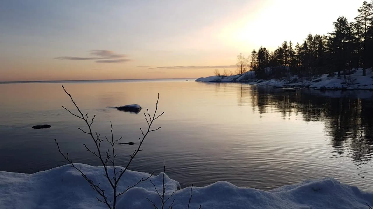 Vy över Storsands camping i vinterlandskap, med snöklädd mark och en himmel i skymningsljus.