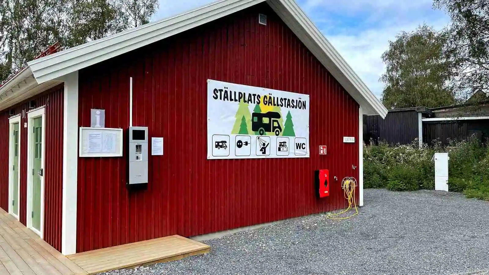 En träbyggnad med en dörr och träpanel, troligen en del av faciliteterna vid ställplats Gällstasjön.