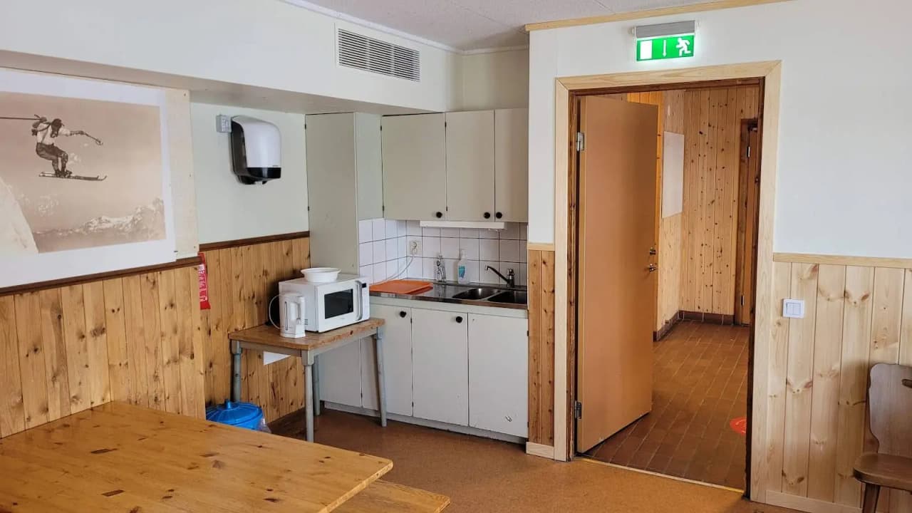 Ett rum på Idre Fjäll Camping med trägolv, träpanel på väggarna och i taket. En säng är placerad mot ena väggen, omgiven av rustik inredning och möbler i trä.