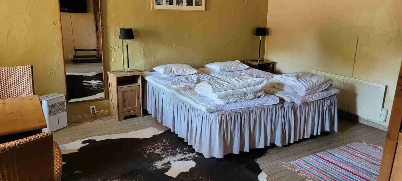 En mysig stuga med träinredning på Grottbyns camping, innehållande en enkelbädd med textilier, naturnära golv och mjuk belysning.