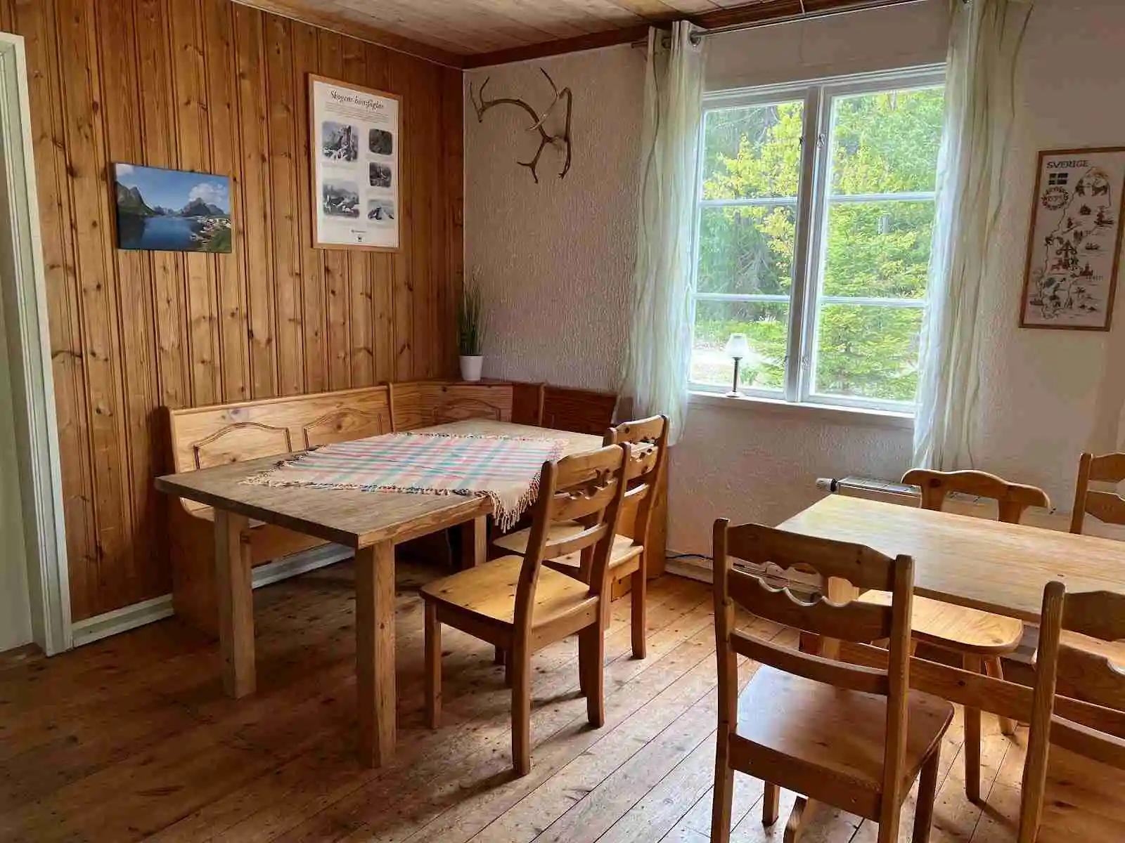 En mysig interiörbild som visar ett rum med träinredning. Det finns ett trägolv, ett träbord och trädetaljer i rummet, vilket ger en varm och inbjudande atmosfär i Nya Skogsgården camping och vandrarhem.