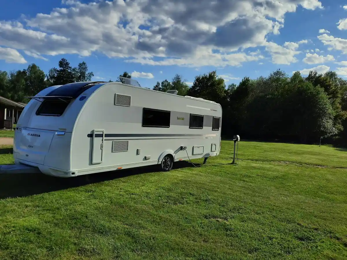 En campingplats med flera husvagnar uppställda på gräsplan under en klar himmel.