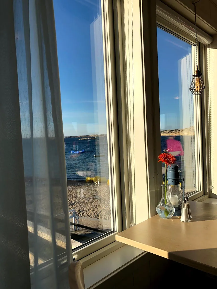 En skål med glass i en solig stuga vid havet, solljuset strömmar in genom gardinerna.