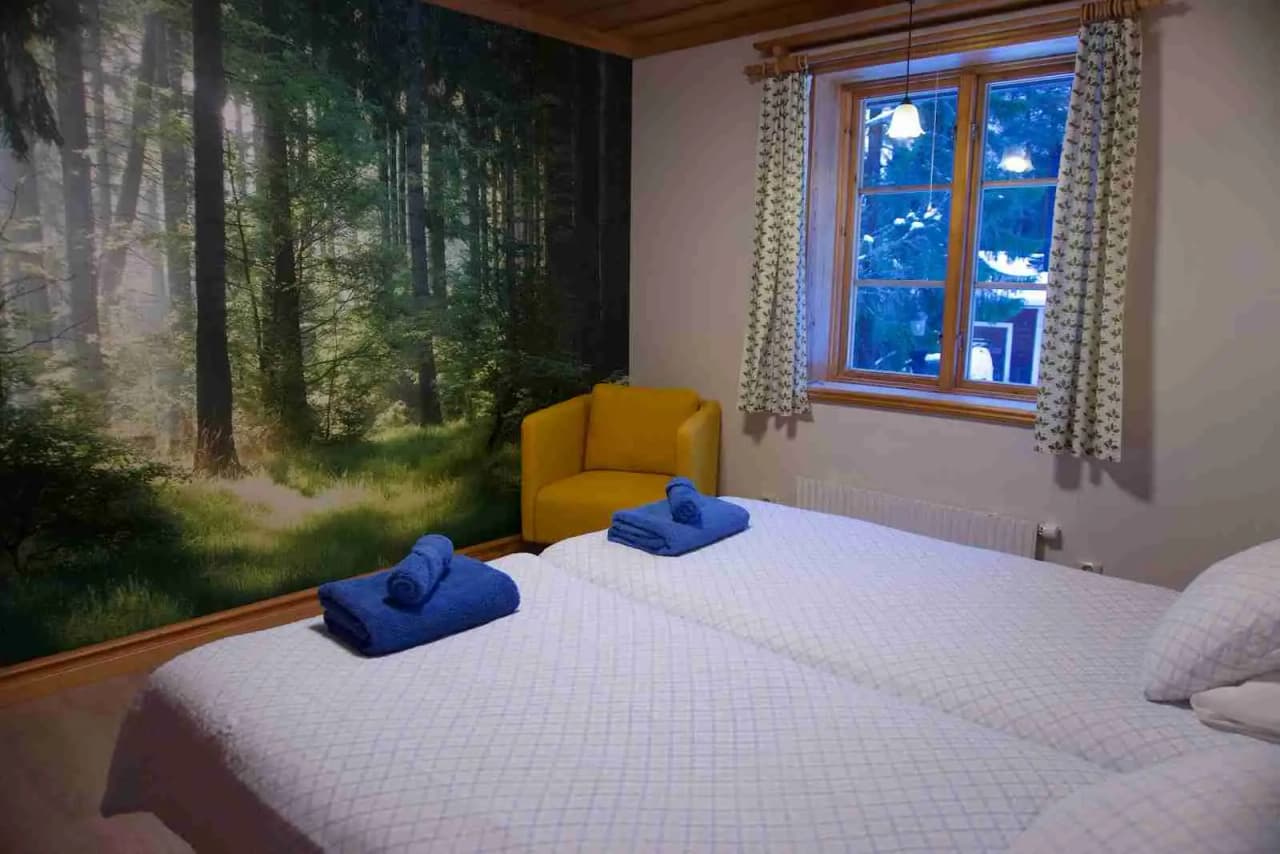 Ett rustikt sovrum i Skålsjögården Timber Lodge, inrett med träpaneler och möbler. Rummet innehåller en säng med vit bäddning, omgiven av trämöbler och ett tak med träbjälkar.