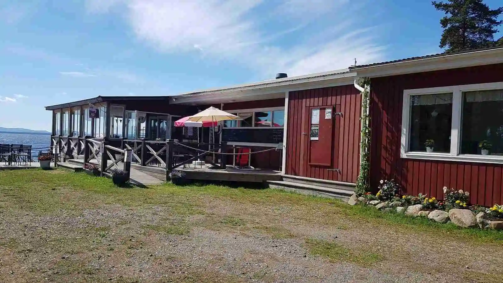 Alt-text: Uteservering med bord och stolar i skuggan vid Norra Dellen Familjecamping.