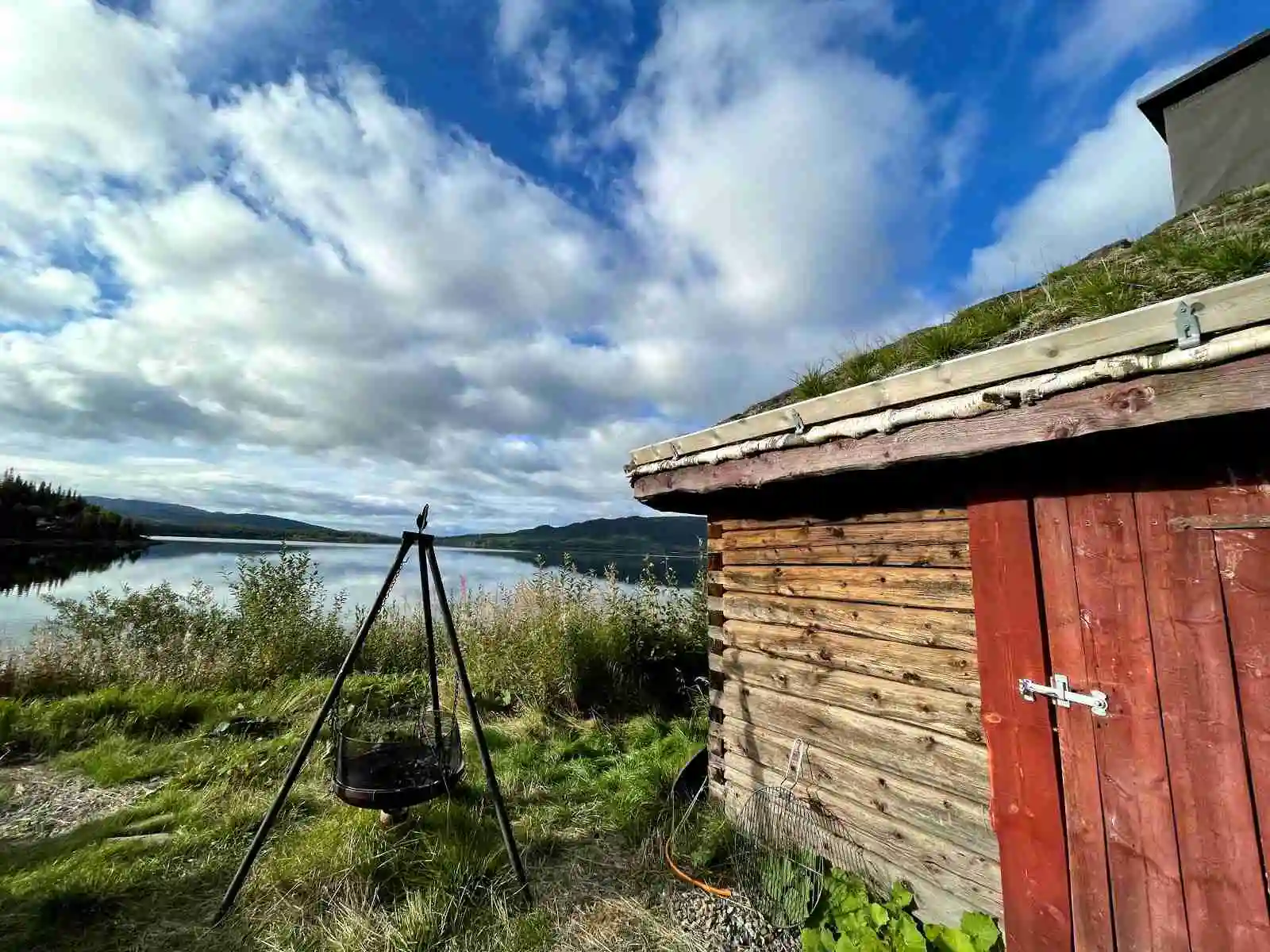 En lantlig campingplats omgiven av mjuka kullar och öppna gräsmarker under en molnig himmel.