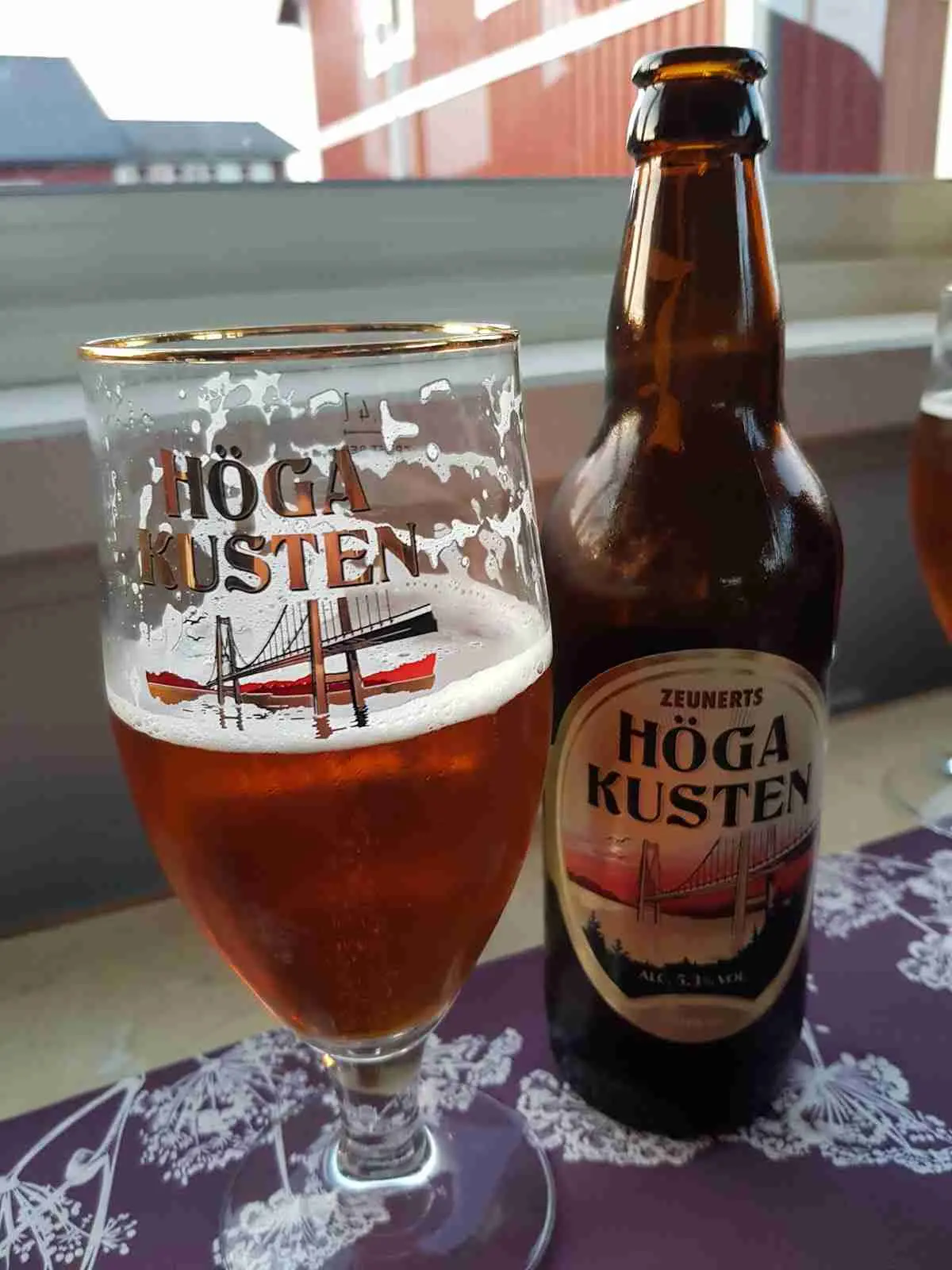 Flaskor med alkoholhaltiga drycker står uppradade på en hylla, omgivna av dricksglas, på Docksta Vandrarhem & Camping Kustladan, vilket ger en inbjudande atmosfär för besökare.