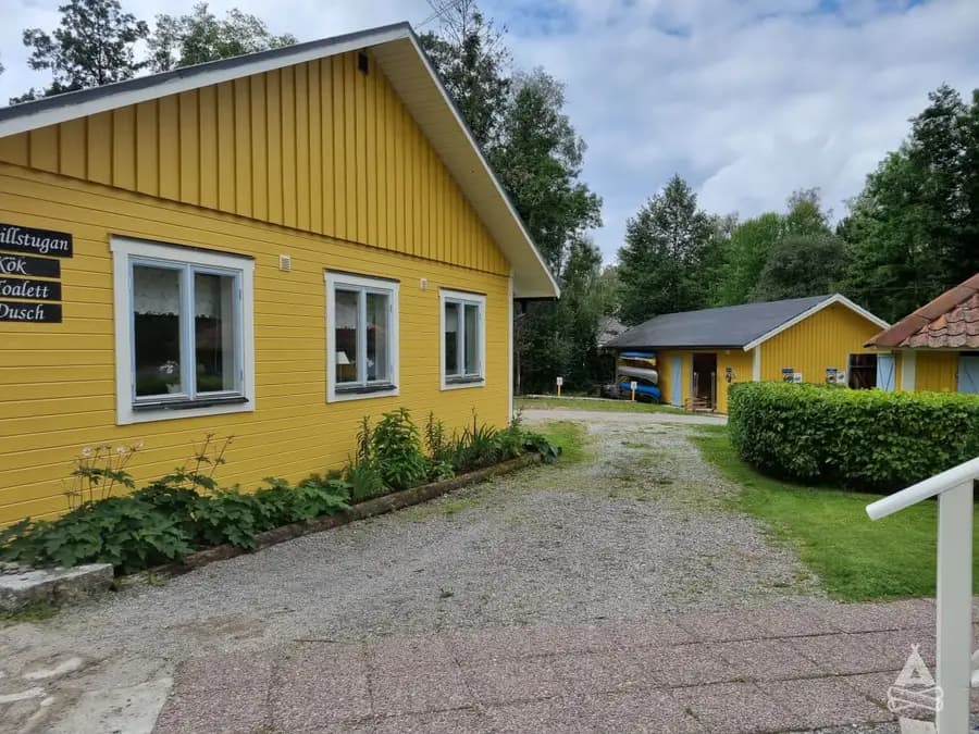 En pittoresk stuga på Sofielund vandrarhem & camping, omgiven av buskar och en välskött gräsmatta.