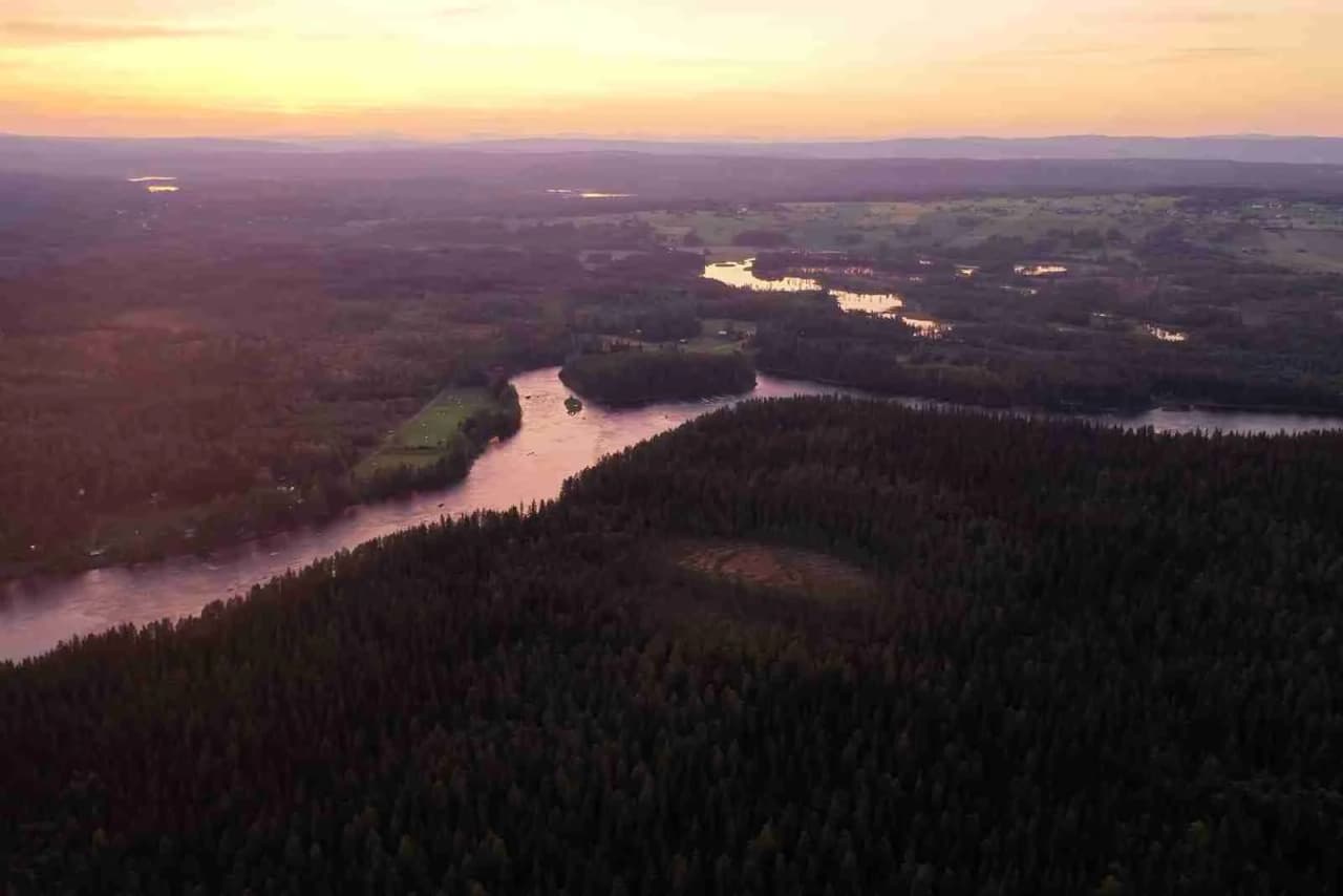 Flygbild över Kvissleströmmens fiskecamping som visar ett frodigt vildmarkslandskap med vattendrag och våtmarker omgivna av tät skog.