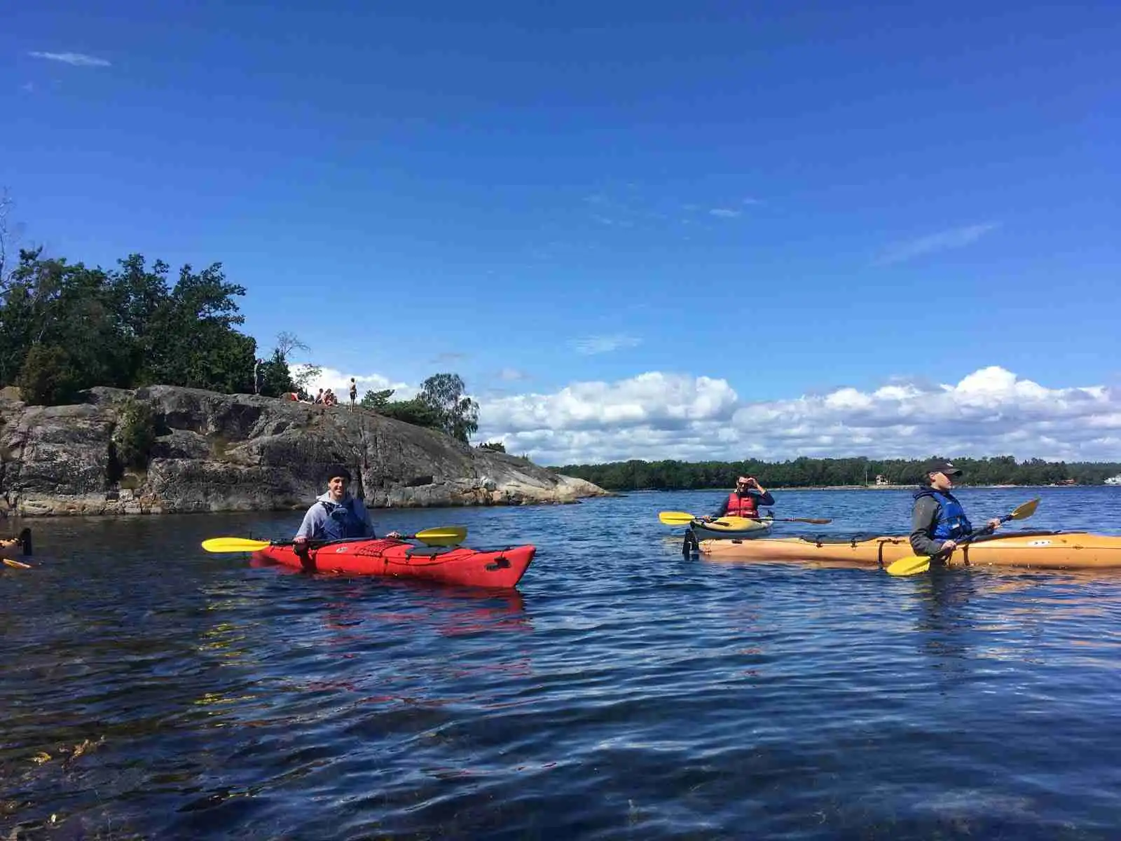 En person paddlar en kajak på vattnet vid Norraryds camping, omgiven av grönska och lugn natur.