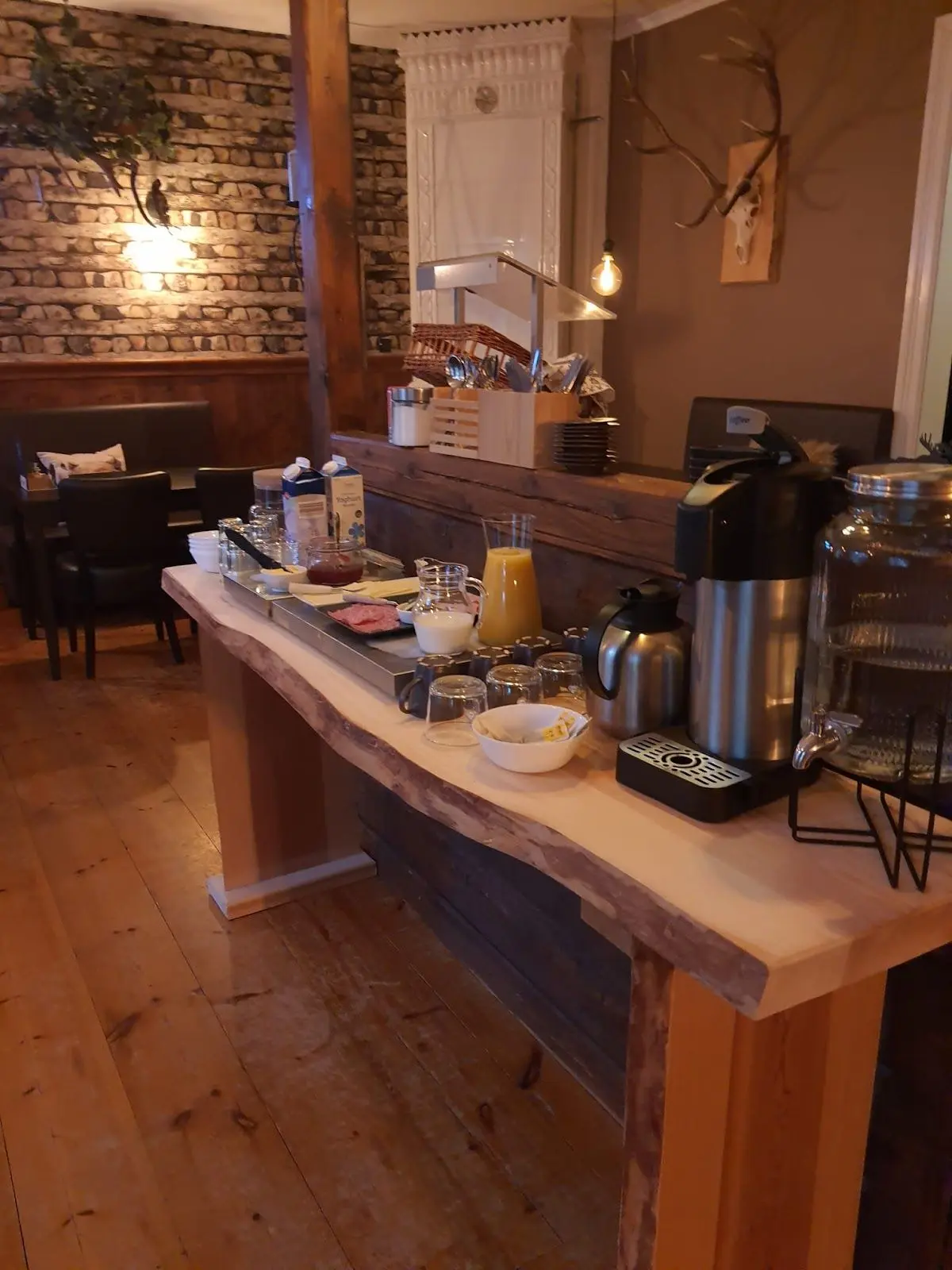 En mysig interiörbild av Wildlife Sweden Camp Ängra med ett träbord i förgrunden. Bordet bär på serveringsföremål och delikatesser, omgivet av vacker träinredning med träplankor och lackad yta som ger en rustik och inbjudande atmosfär.