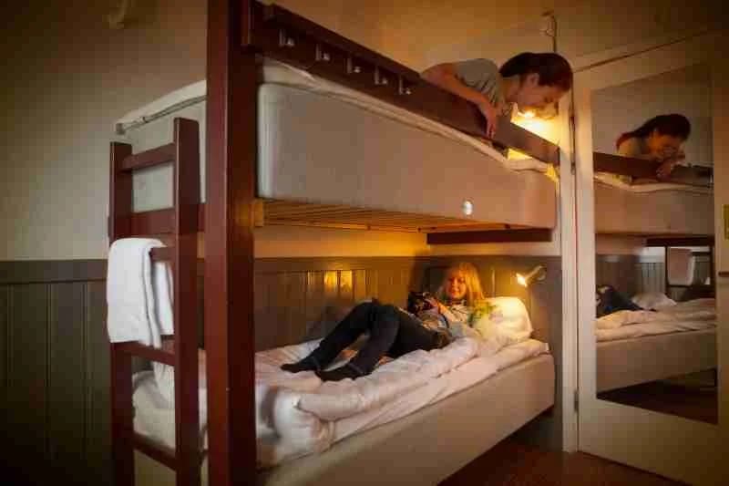 En ljus sovsal i Lisebergsbyn med enkelsängar i våningssängsform, utrustade med vit sängkläder och enkla träramar, inredningen är enkel och funktionell idealisk för backpackers och små grupper.