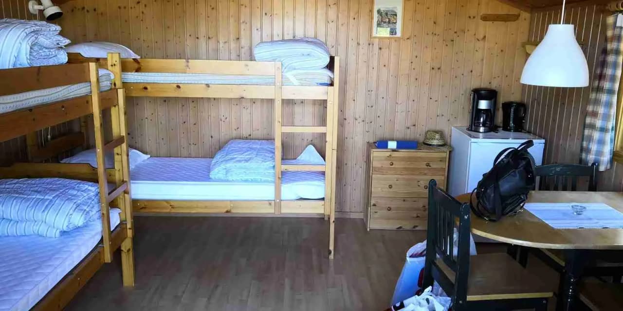 En campingstuga med träinredning som visar en våningssäng, trägolv och enkel rumdesign.