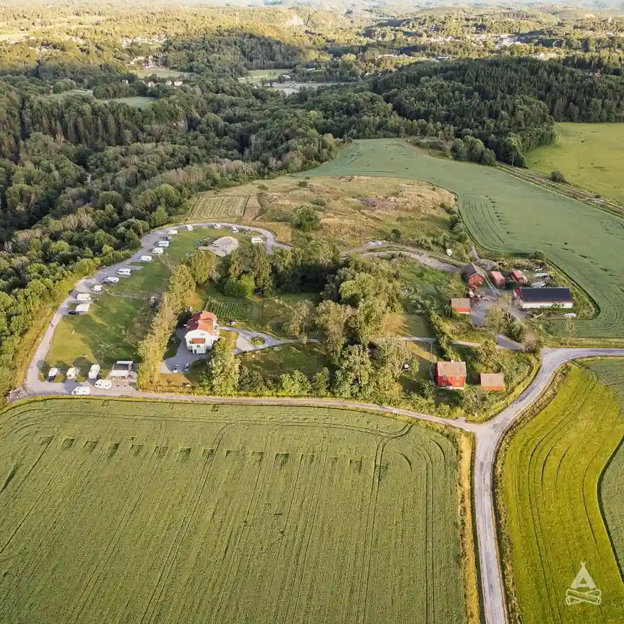 Flygbild över Brålands Gård Nature Camp som visar ett naturlandskap med vidsträckta ängar och åkermark i en lantlig miljö.